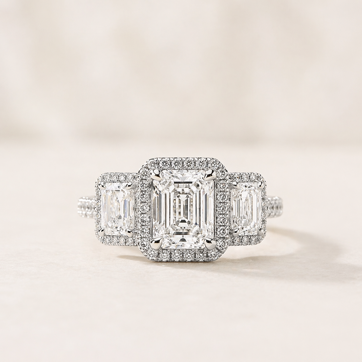 A white gold three stone emerald cut diamond engagement ring on a white background
