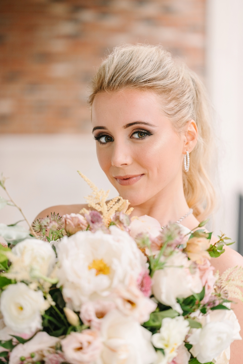Bride holding flowers looking at the camera with diamond hoop earrings on