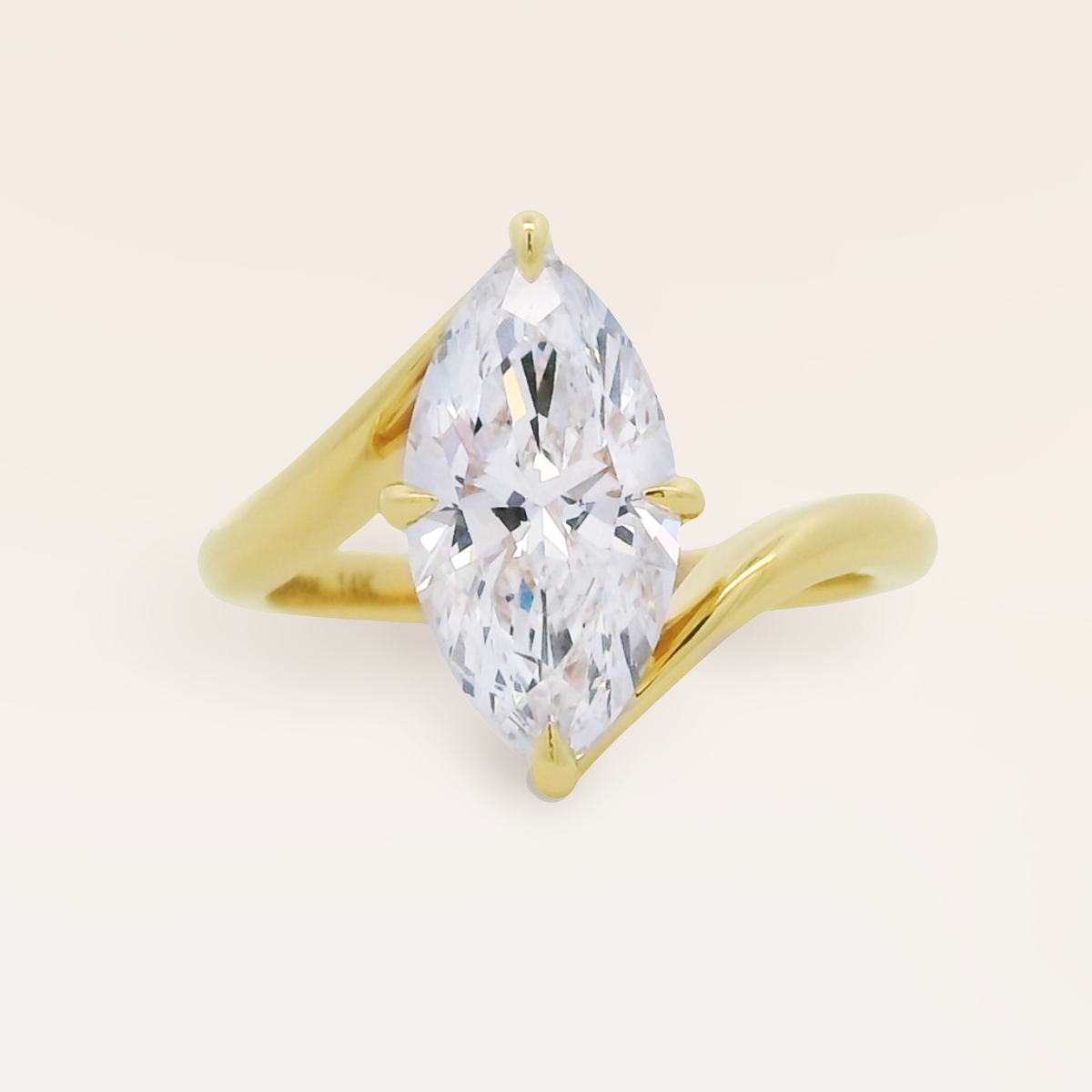 A custom-made yellow gold ring featuring a large marquise-cut clear gemstone in a bypass-style setting, shown on a clean, light beige background.
