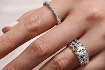 Hand wearing white gold rings with a plain background