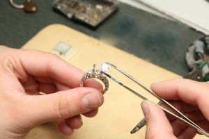 Close up of a jeweler putting a diamond into an engagement ring